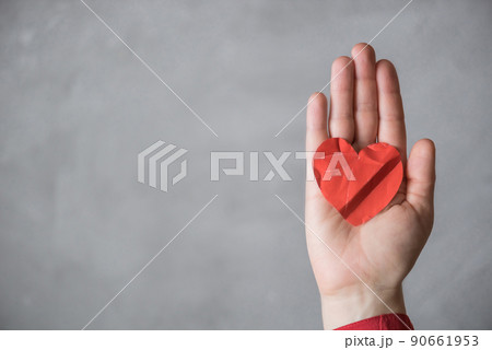 woman hand with crumpled paper red heart against the concrete floor.  Broken relationships in bad Valentine's day. concept. 90661953