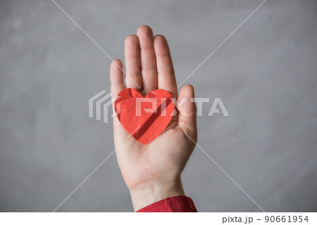 woman hand with crumpled paper red heart against the concrete floor.  Broken relationships in bad Valentine's day. concept. 90661954