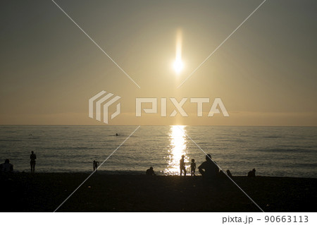 Silhouettes of people resting by the sea in the rays of the evening sun. Russia Sochi November 2021. 90663113