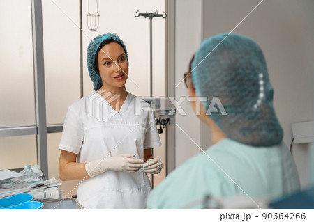 Two nurses in uniform talking in operating room before surgery in clinic Two nurses in uniform talking in operating room before surgery in clinic 90664266