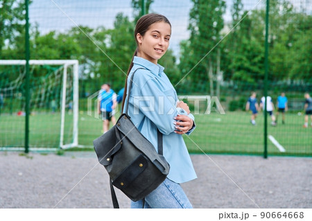 Portrait of teenage female student looking at camera, school stadium background 90664668