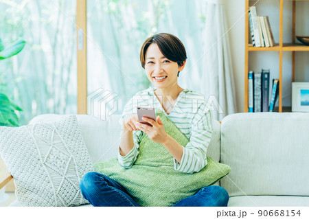 リビングでスマホを見るミドルの女性 リビングでスマホを見るミドルの女性 90668154