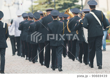 A wind instrument parade - people in costumes walking on the street holding musical instruments 90669439
