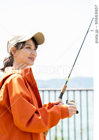 青空の下で趣味の釣りを楽しむ笑顔の若い女性 90669907
