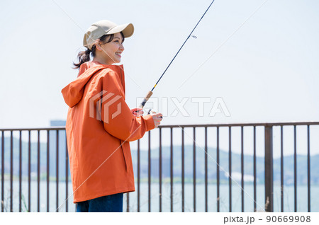 青空の下で趣味の釣りを楽しむ笑顔の若い女性 90669908
