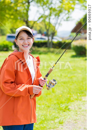 青空の下で趣味の釣りを楽しむ笑顔の若い女性 青空の下で趣味の釣りを楽しむ笑顔の若い女性 90669917