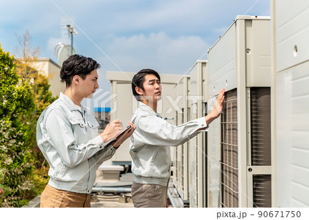 屋上に設置されている空調設備を確認する技術者 90671750