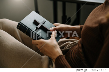 Woman sitting and studying the scriptures.The  wooden cross in the hands. Christian education concepts The Holy Scriptures open and pray to God.. 90673422