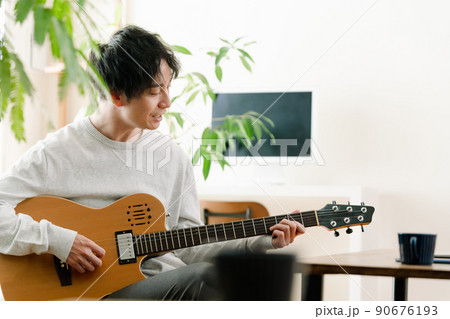 リビングでギターを弾く男性 90676193