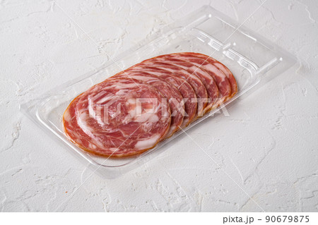Sliced smoked meat vacuum package, on white stone table background, with copy space for text 90679875
