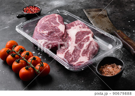 Beef steak in vacuum packing. Market Chuck Eye Roll, on black dark stone table background 90679888