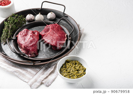 Raw beef meat steak with herbs, on white stone table background, with copy space for text 90679958