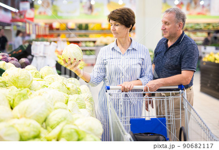 Mature couple husband and wife choose cabbagehead in the vegetables section of the supermarket 90682117