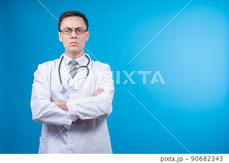 Strict doctor in glasses against blue backdrop Strict doctor in glasses against blue backdrop 90682343