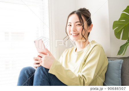 窓際でスマホを操作する女性 90686507