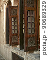 Windows with beautiful old wooden folding shutters on the walls of a adobe house, opening up in the courtyard   in the old city of Yazd 90689329