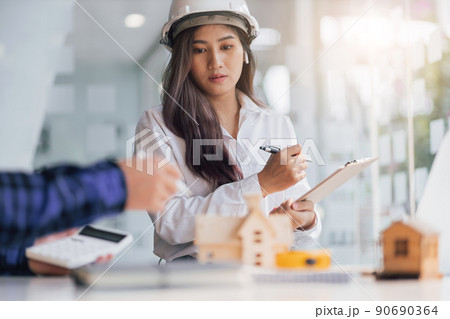 Happy female architect designer in the office works with her colleagues, engineers, contractors together to design and cost housing projects. Happy female architect designer in the office works with her colleagues, engineers, contractors together to design and cost housing projects. 90690364