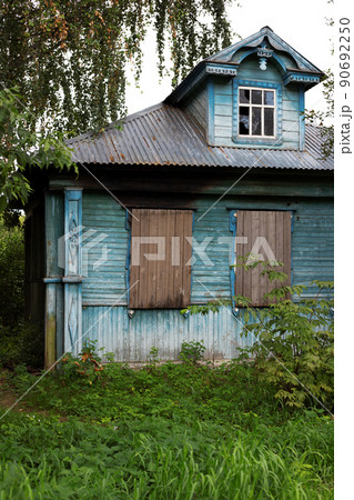 Front exterior old historic abandoned wooden painted blue house with boarded up windows. 90692250