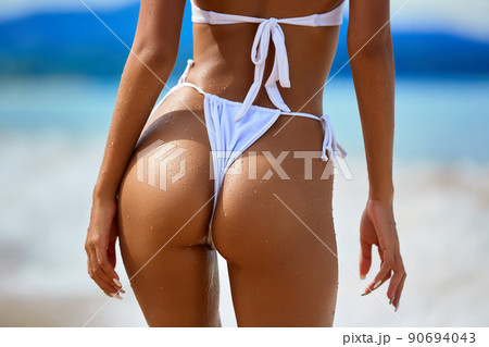 Sexy model's ass in white bikini on the blue water background Sexy model's ass in white bikini on the blue water background 90694043