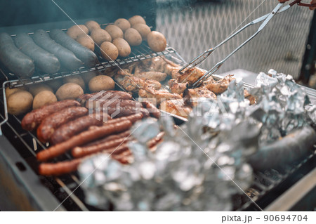 Close up view of men hands roasting barbecue on fire grill. Close up view of men hands roasting barbecue on fire grill. 90694704