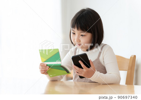 預金通帳とスマートフォンを見つめる女の子 90697340