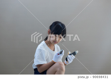 夏の自宅でニッパーを持って作業している小学生の女の子の様子 90698431