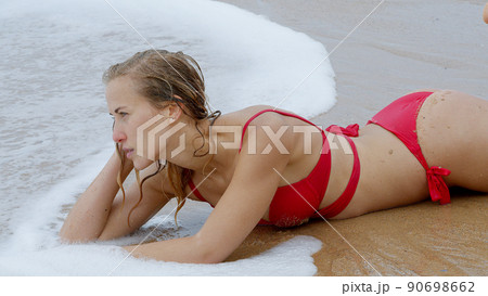Sexy woman in a bikini relaxes on a sandy beach at the ocean 90698662