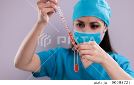 Female doctor examines a blood sample Female doctor examines a blood sample 90698725