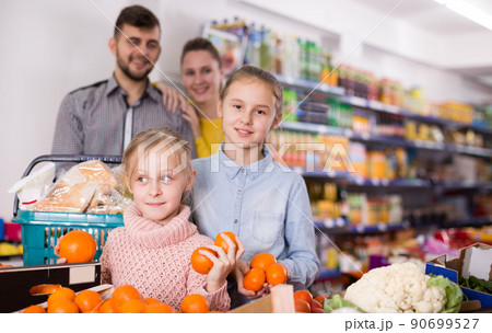 Smiling little girl choosing fresh mandarins Smiling little girl choosing fresh mandarins 90699527