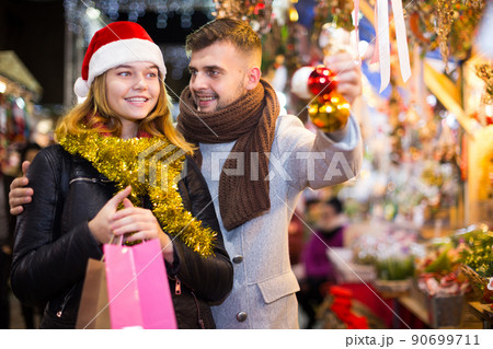 Joyful couple in Christmas hat with Christmas toys at fair 90699711