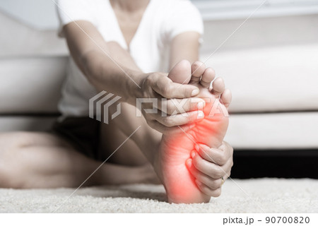 Asian woman feeling pain in her foot at home Asian woman feeling pain in her foot at home 90700820