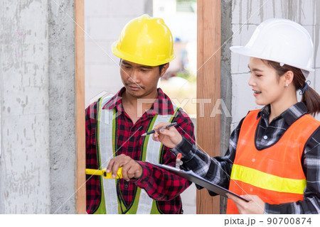 Male industrial builder workers installation process measuring wooden door with measure tape 90700874