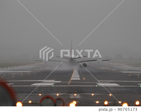 雨天の誘導灯が点灯する滑走路に着陸した飛行機 90705173