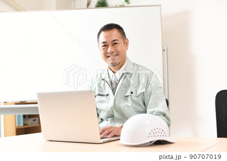 パソコン操作をする作業服を着た男性 90707019
