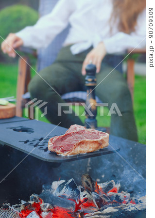 T-bone steak on barbecue grid over hot charcoal 90709109