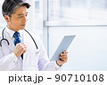 施設内でタブレットPCを持って立っている白衣の医師 90710108