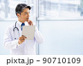 施設内でタブレットPCを持って立っている白衣の医師 90710109