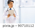 施設内でタブレットPCを持って立っている白衣の医師 90710112