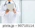施設内でタブレットPCを持って立っている白衣の医師 90710114