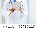 施設内でタブレットPCを持って立っている白衣の医師 90710115