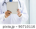 施設内でタブレットPCを持って立っている白衣の医師 90710116