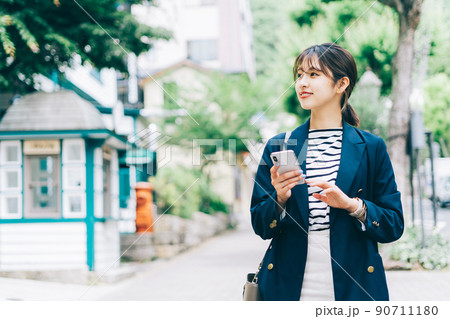スマホを持って街を歩く女性 スマホを持って街を歩く女性 90711180