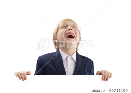 Cheerful boy posing with empty white paper board and laughs. Cute blond boy peeking out from behind white board. Cheerful boy posing with empty white paper board and laughs. Cute blond boy peeking out from behind white board. 90711199