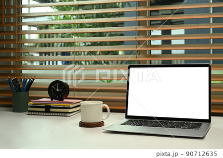 Comfortable home office with laptop computer, coffee cup and supplies on white table 90712635