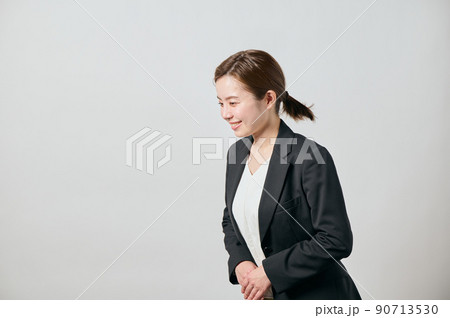 手を前に組みお辞儀をするジャケット姿のビジネスウーマン 90713530