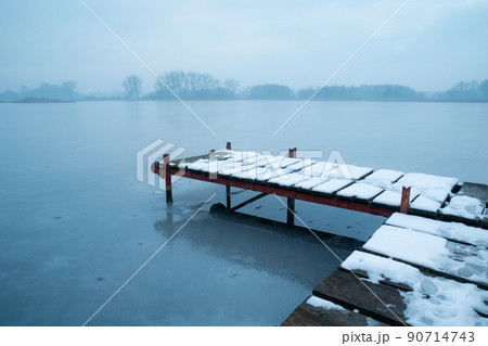 Snow on a pier on a frozen lake Snow on a pier on a frozen lake 90714743