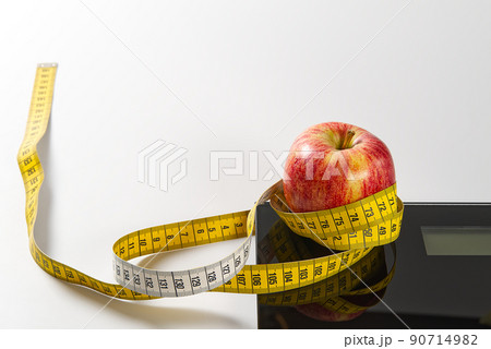 Diet plan, menu or program, tape measure, diet food of fresh fruits on white background, weight loss and detox concept, top view. weight loss concept. Apple and measuring tape. Diet. 90714982