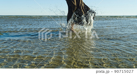 nice legs of a pretty girl walking in water. woman legs, walking on the beach. Legs of a beautiful young girl who runs towards the ocean. Water splashes out 90715027