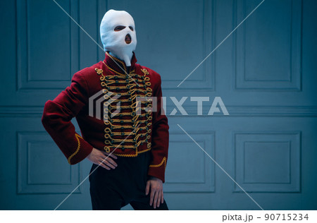 Young man, medieval hussar wearing white colors balaclava on dark blue background. Concept of comparison of eras, art, history. Creative collage. Young man, medieval hussar wearing white colors balaclava on dark blue background. Concept of comparison of eras, art, history. Creative collage. 90715234