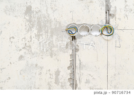 Holes in a concrete wall for installing plastic boxes under sockets. installation of sockets in a concrete wall and wiring. 90716734